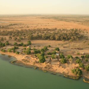 Traditional wooden pirogue sailing on Senegal’s Pink Lake with sand dunes and clear sky in the background