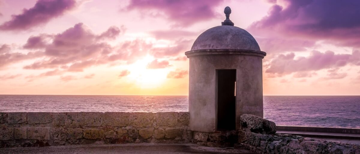 Traveler looking out at the sea from Cartagena’s city walls at sunrise