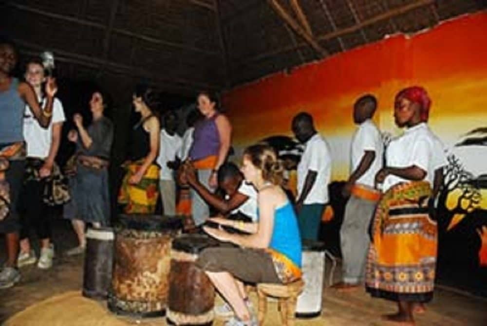 Traveler relaxing on a sun lounger by a pool with palm trees at a lodge near Moshi