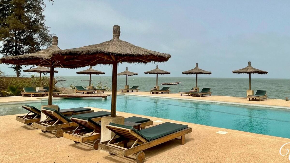 Traveler with luggage walking along a palm-lined path towards departure transfer on the Senegalese coast