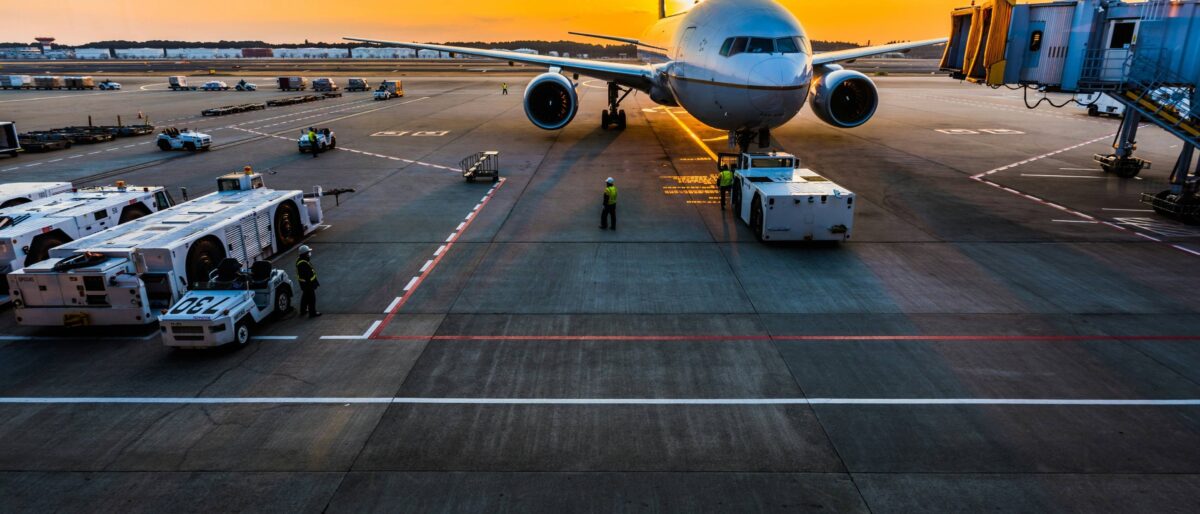 Travelers arriving at Luxor Airport terminal with luggage and a view of the runway and desert in the background