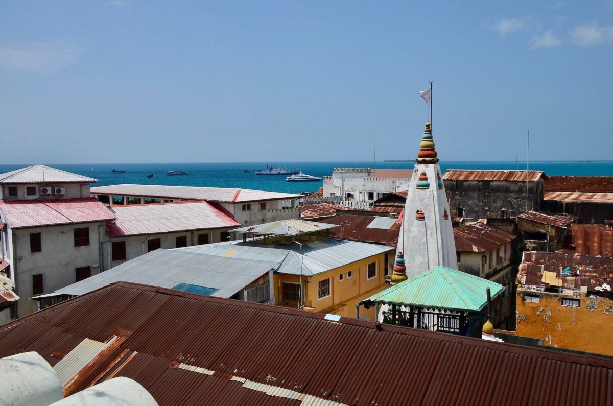 Traveler’s silhouette walking towards a small airport terminal on Zanzibar at sunrise