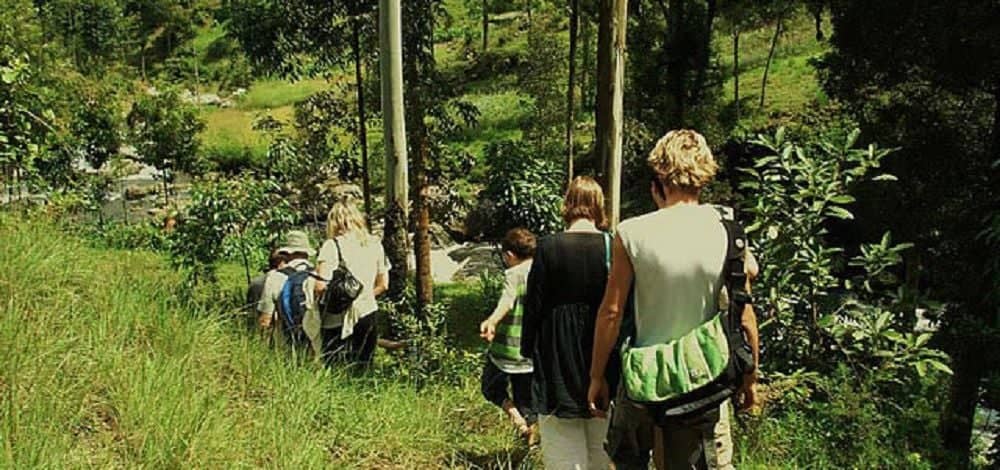 Travelers sitting with Chagga villagers outside a traditional house on the green slopes of Kilimanjaro