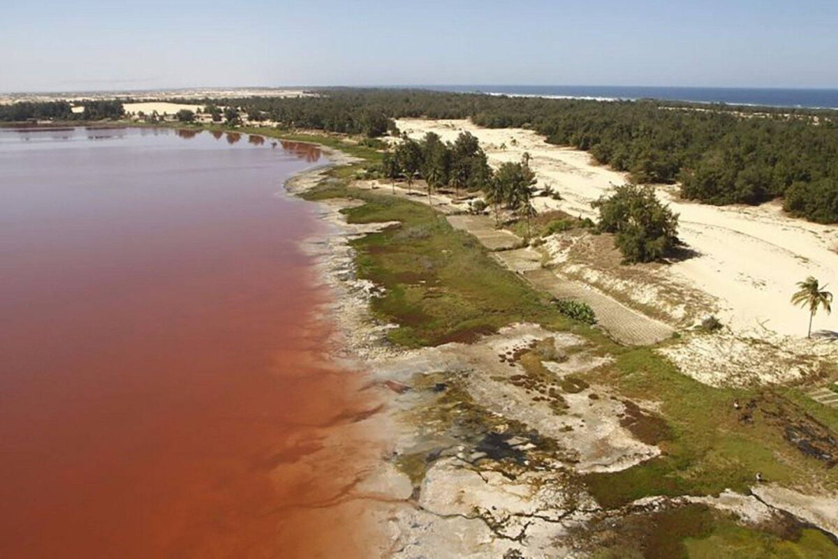 Travellers arriving at pink-tinged Lake Retba near Dakar and walking towards an eco-lodge on a sandy dune