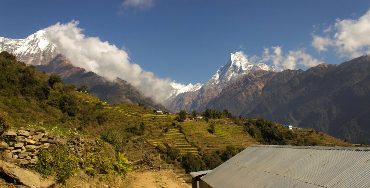 Trekker standing at Annapurna Base Camp at sunrise with snow peaks glowing orange