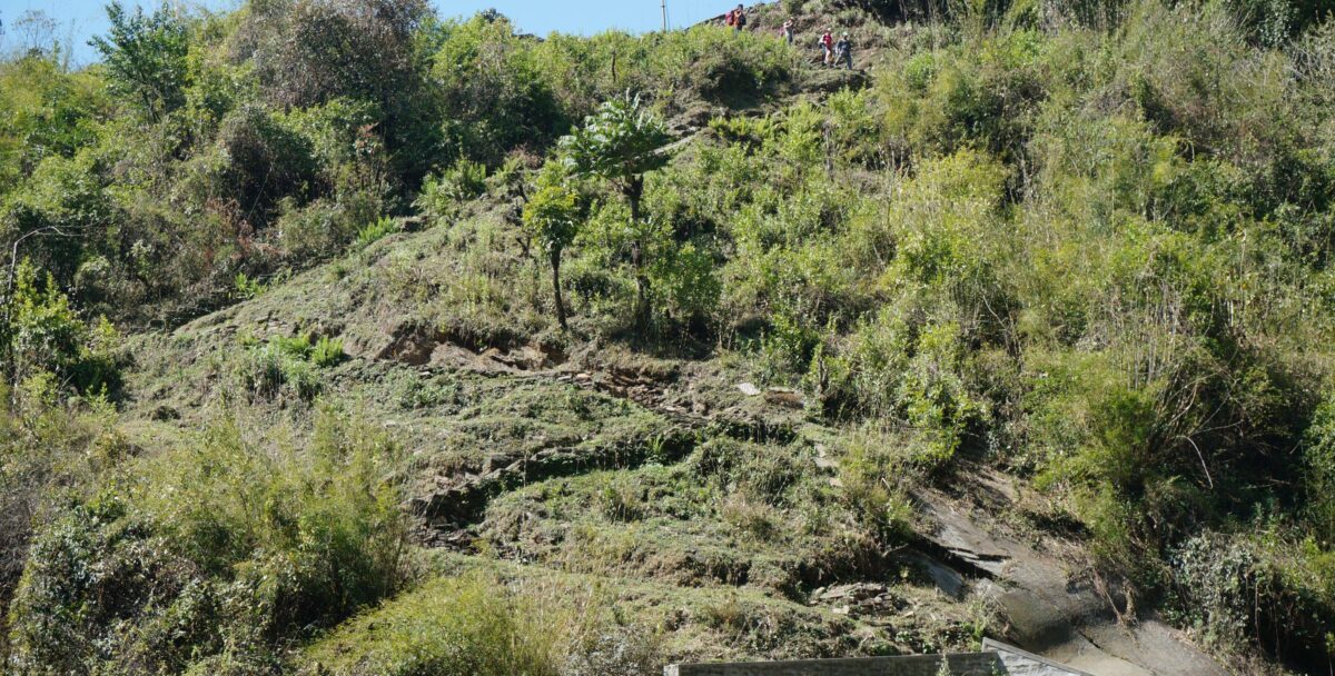 Trekkers relaxing in natural hot springs by a river near Jinuwa surrounded by green forest
