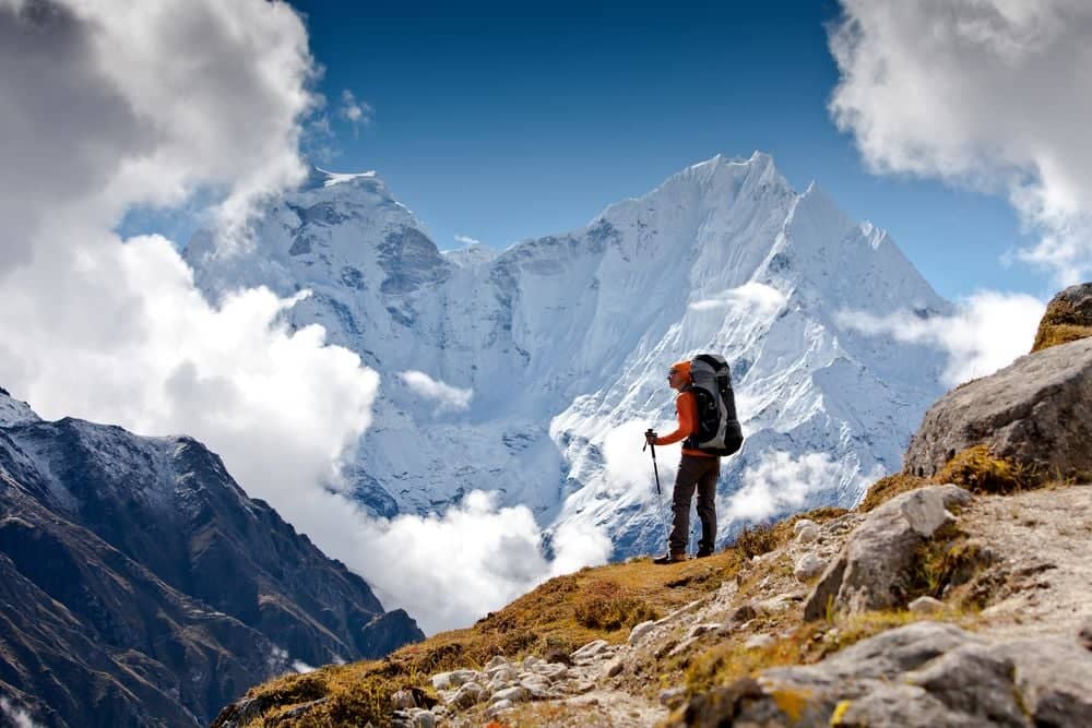 Trekking group walking along a mountain trail towards the snow-covered peaks of the Annapurna range under a clear blue sky in Nepal