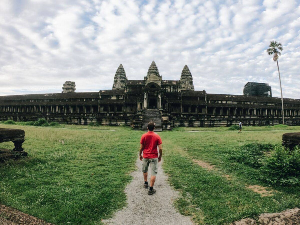 Tuk-tuk driving along the causeway towards the stone gate of Angkor Thom with carved faces