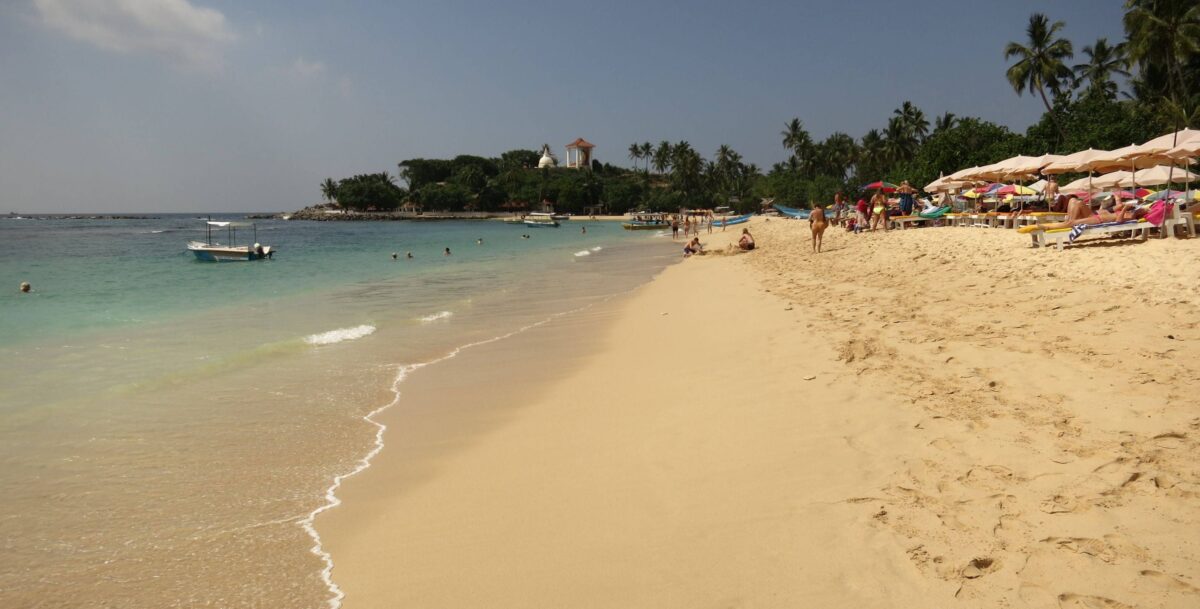Turquoise bay at Unawatuna with families swimming and relaxing under palm trees