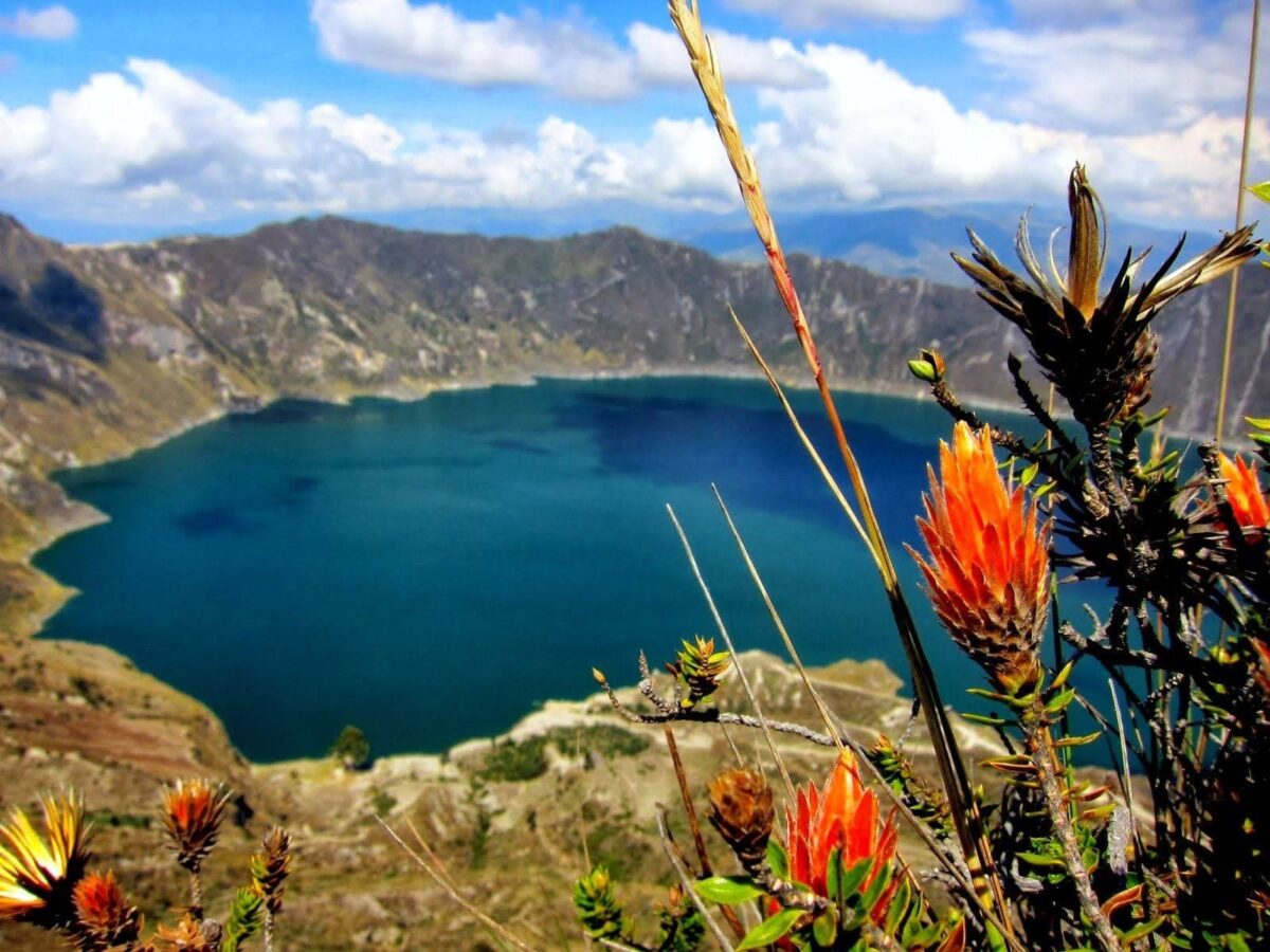 Turquoise Quilotoa crater lagoon surrounded by steep crater walls under a cloudy sky