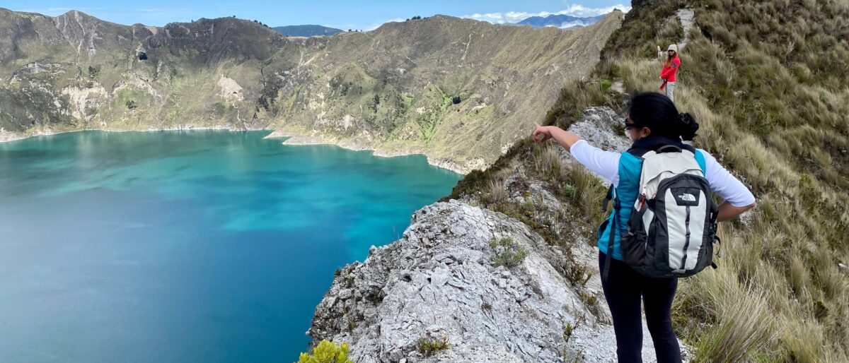 Turquoise Quilotoa crater lake surrounded by steep volcanic walls under a blue Andean sky