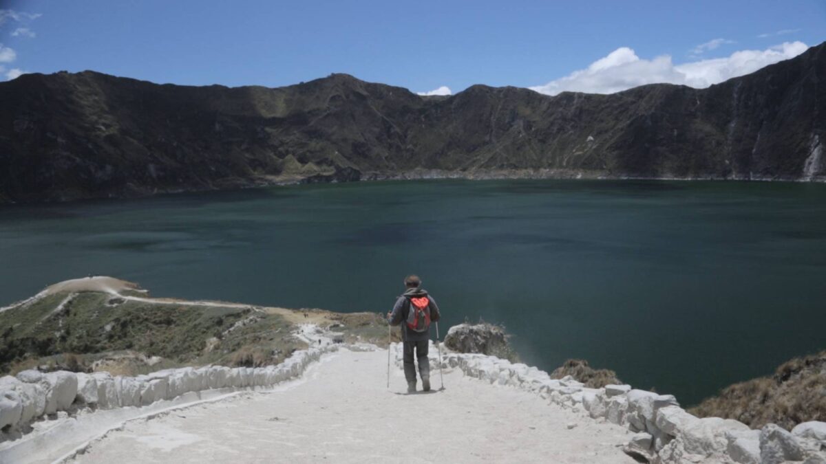 Turquoise waters of Quilotoa crater lake surrounded by steep green and rocky slopes in the Ecuadorian Andes