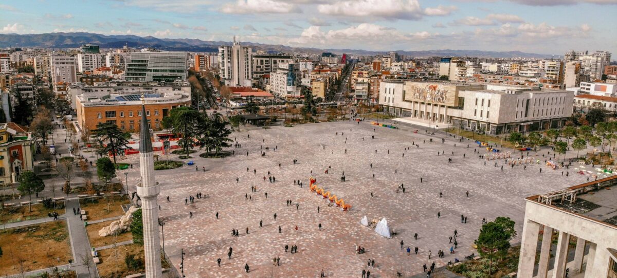 View of an airplane on the runway at Tirana International Airport with mountains in the background