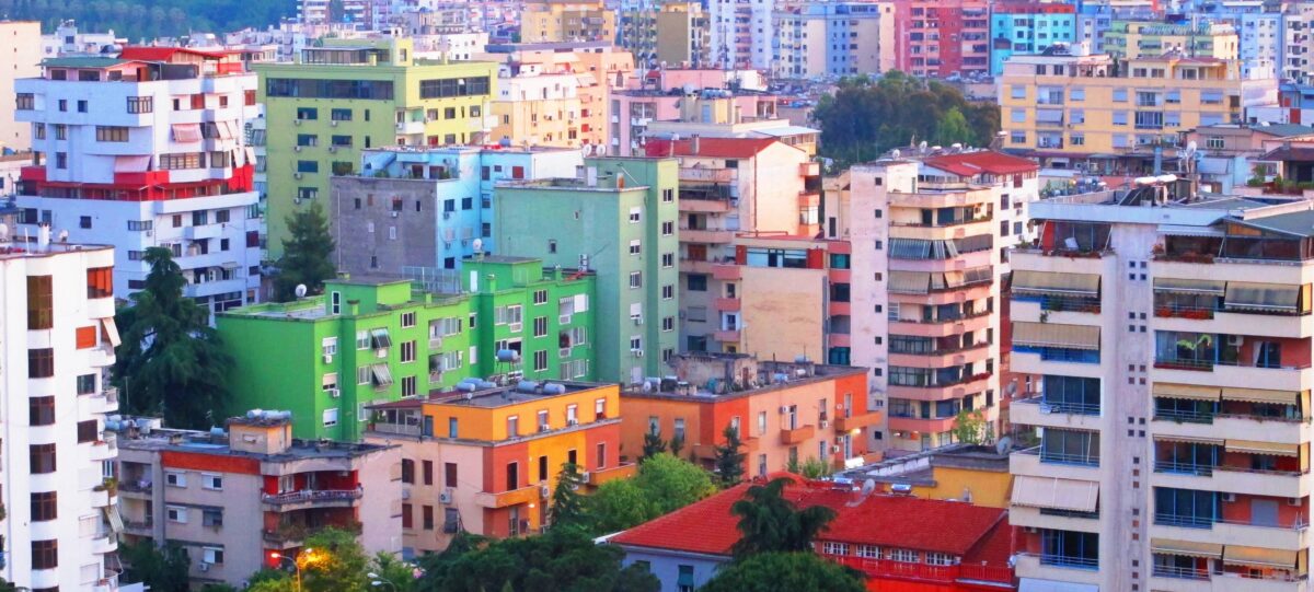 View of an airplane taxiing on the runway at Tirana International Airport with mountains in the background