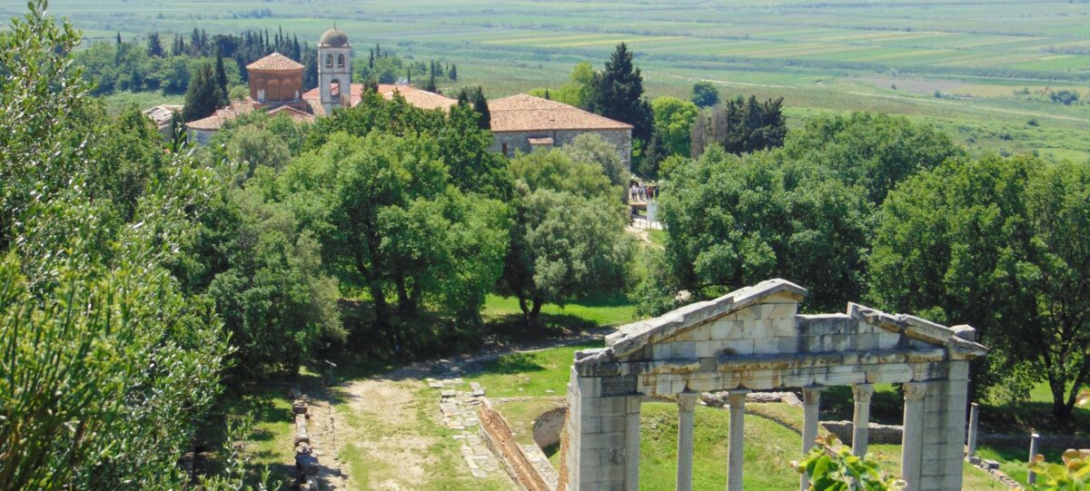 View of Ardenica Monastery complex on a hilltop with stone buildings, red-tiled roofs and surrounding green countryside in Albania