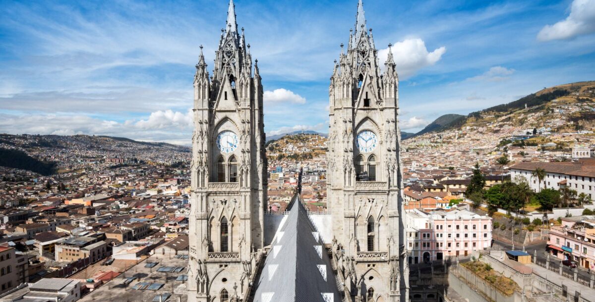 View of colonial Quito with historic churches and tiled rooftops set against surrounding Andean hills