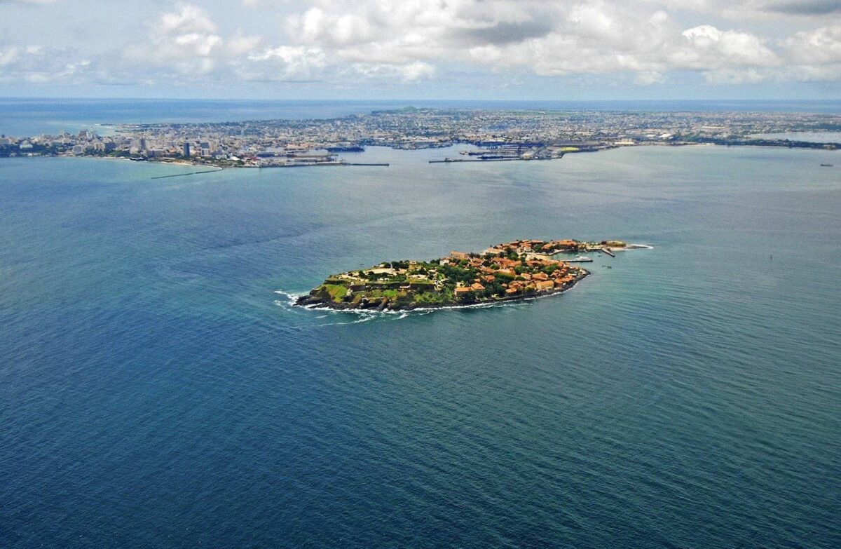 View of Gorée Island’s colorful colonial houses and the sea, with a ferry linking the island to Dakar in the background