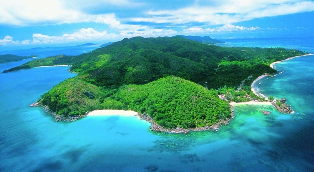 View of Praslin island coastline with turquoise sea, tropical greenery and granite rocks