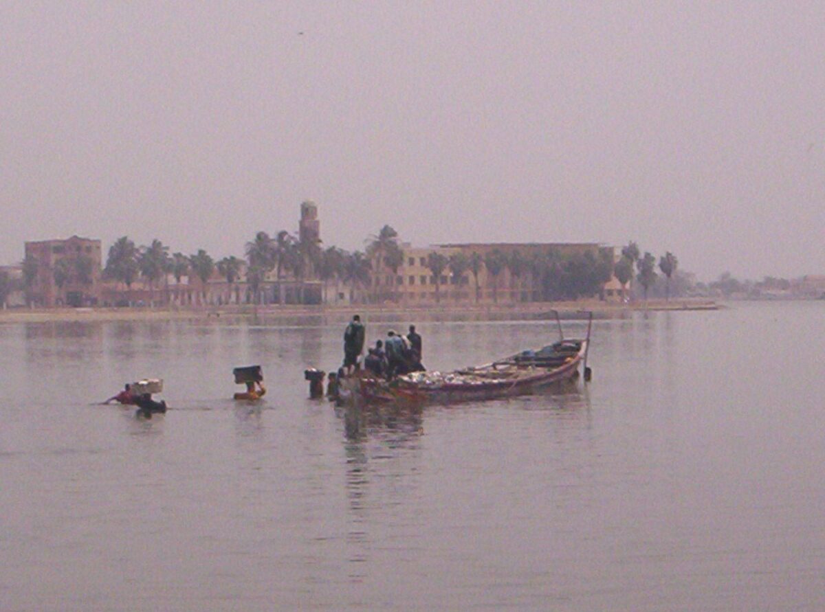 View of Senegal’s Pink Lake with vivid rose-colored water meeting pale sand dunes under a clear sky