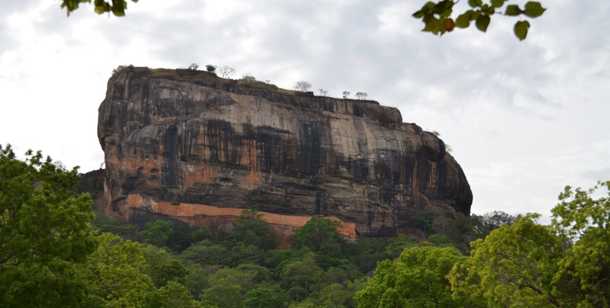 View of Sigiriya Lion Rock fortress rising above green jungle with ancient palace ruins on top