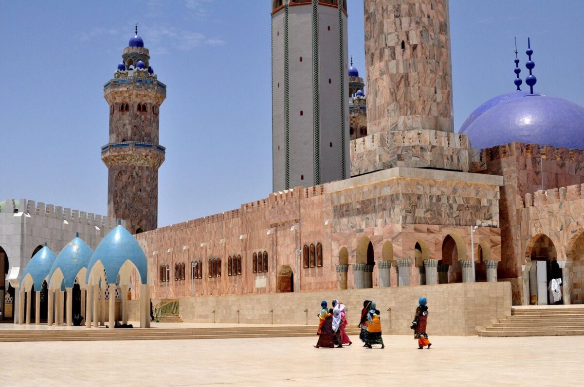 View of Touba’s large mosque with tall minarets and white facades under a bright blue West African sky