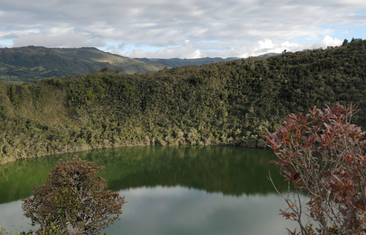 View over the emerald-green Guatavita crater lagoon surrounded by lush hills