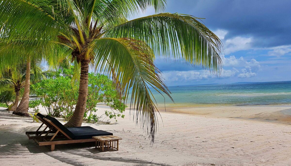 White-sand beach and turquoise sea on Koh Rong Samloem with wooden bungalows nestled among palm trees