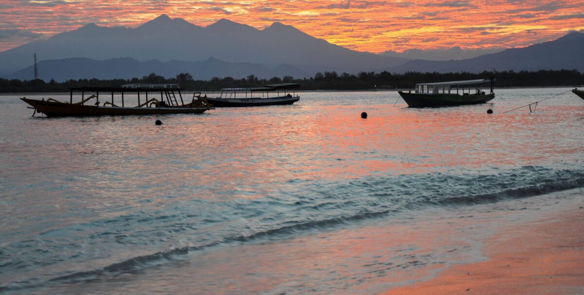 White sand beach on Gili Air with clear turquoise water and a relaxed beachfront bar at sunset
