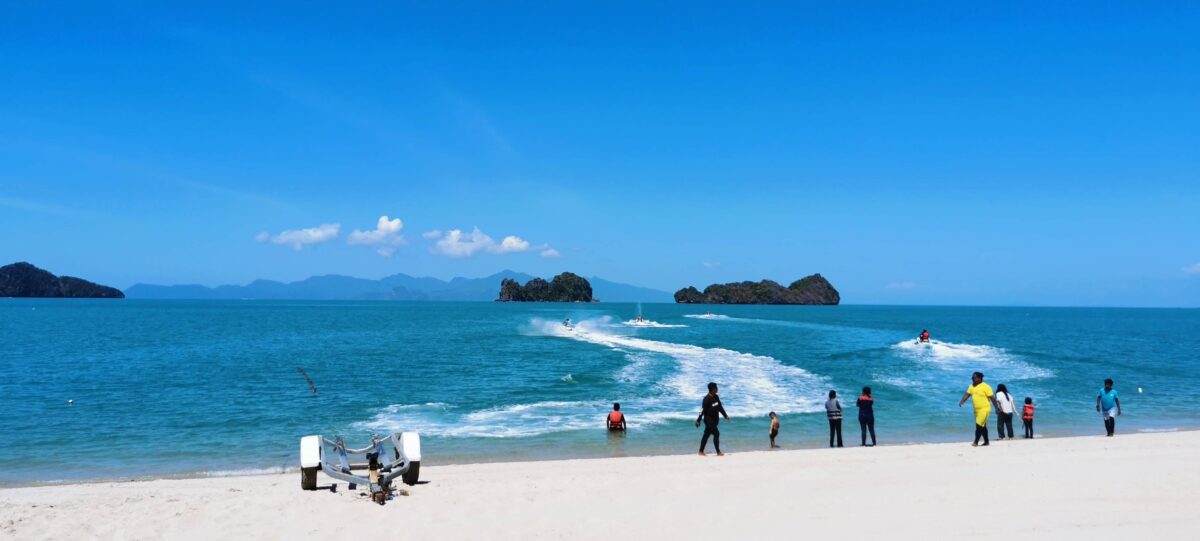 White-sand beach on Langkawi Island with calm turquoise water and green hills in the distance