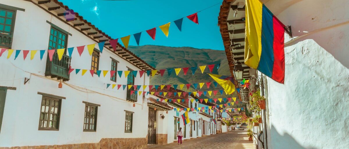 Wide cobbled Plaza Mayor in Villa de Leyva surrounded by white colonial buildings under a blue sky