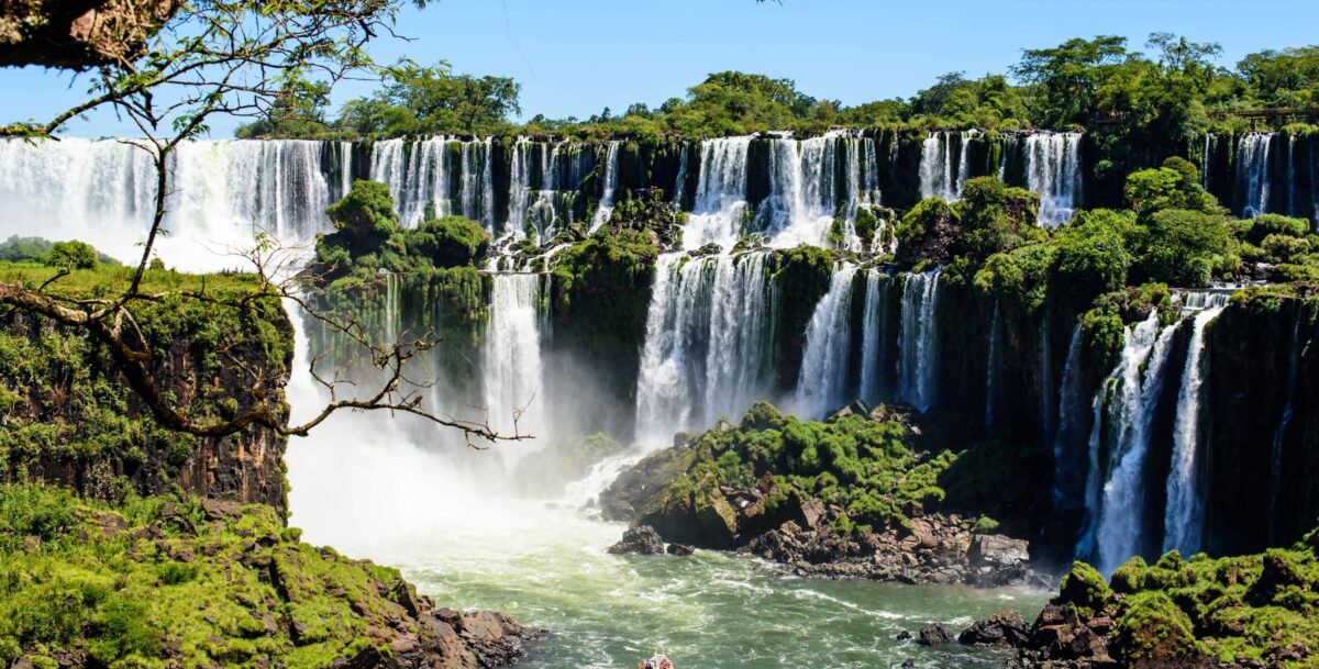 Wide panoramic view of Iguazu Falls pouring over lush green cliffs on the Brazilian side