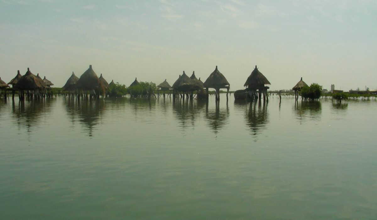 Wooden pirogue approaching the shell-covered island and stilted granaries of Fadiouth near Joal, Senegal
